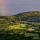 Photographie de la campagne de Haute Savoie sous un ciel d'orage traversé par un arc en ciel