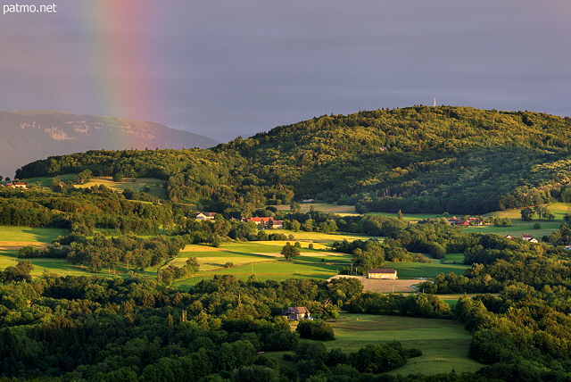 Photographie de la campagne de Haute Savoie sous un ciel d'orage travers par un arc en ciel