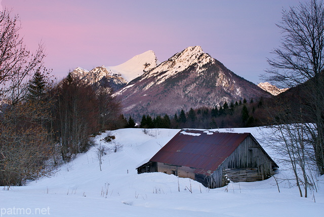 Photo d'une vieille grange dans un paysage d'hiver au crépuscule dans le Parc Naturel Régional du Massif des Bauges