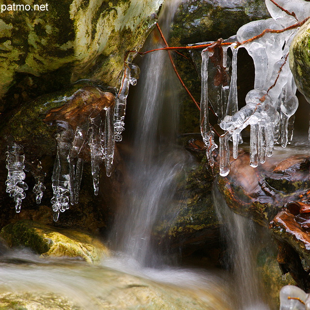 Image d'une petite chute d'eau entoure de glaons dans le ruisseau du Fornant en Haute Savoie