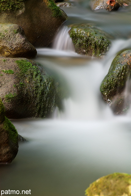 Photo en pose longue de l'eau vive cascadant entre les rochers dans le ruisseau du Fornant