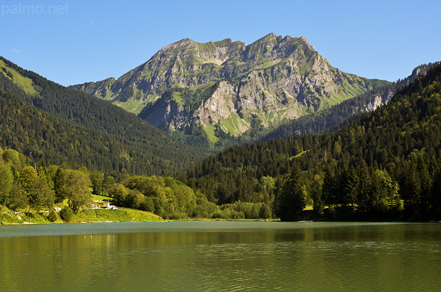 Photograph of Roc d'Enfer mountain over the green water of Bellevaux lake