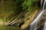 Waterfall, mossy rocks and vegetation in summer along river Cheran