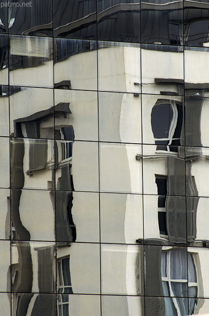 Photo de reflets déformés d'un immeuble sur une façade vitrée à Annecy