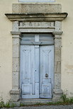 Image d'une ancienne porte en bois entourée de pierre sur une maison ardéchoise