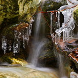 Image d'une petite chute d'eau entoure de glaons dans le ruisseau du Fornant en Haute Savoie