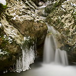Photographie d'une cascade entourée de stalactites de glace dans le torrent du Fornant en Haute Savoie
