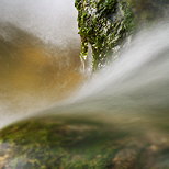 Photo en gros plan de l'eau circulant entre des rochers moussus dans le Fornant